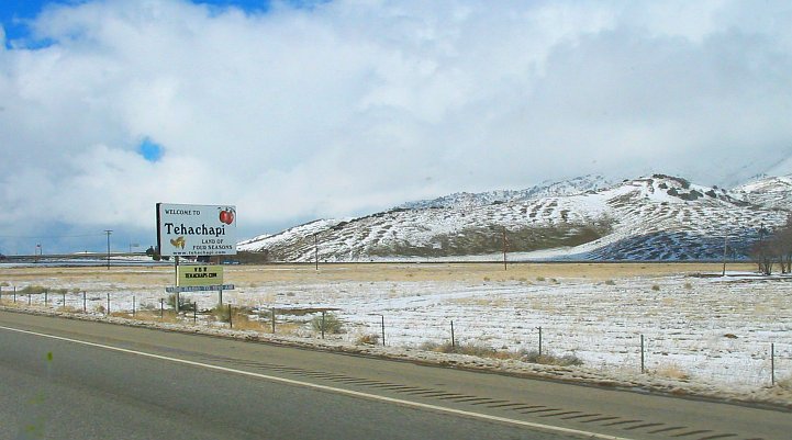 Welcome to Tehachapi Land of Four Seasons sign with snowy hills behind